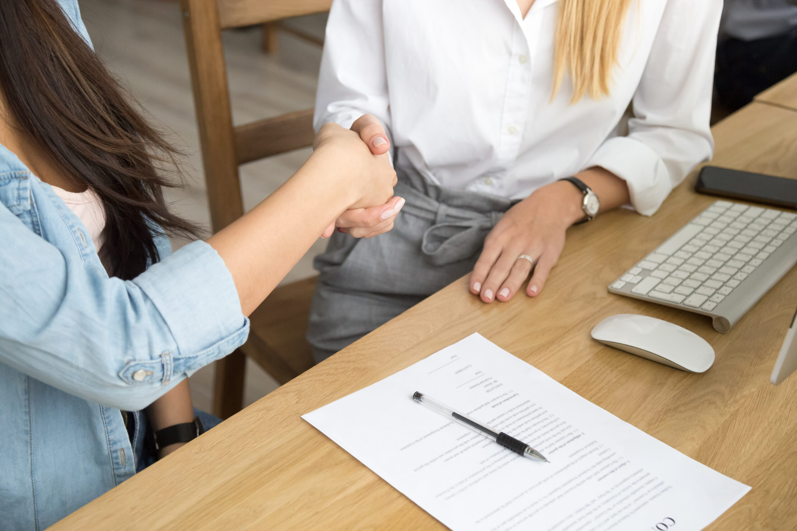 Two women partners handshaking after signing business contract a